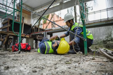 İnşaat alanındaki inşaat işçisinin iş yerinde ilk yardım kazası. İskeleden düşen kaza Foreman çalışanların ilk yardım çantasındaki kazaya yardım etti.