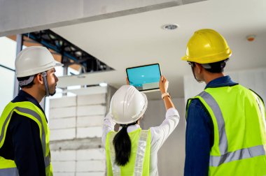 İnşaat mühendisi ekibi inşaat ve teftişi taramak için tabletlerle teknoloji yazılımı kullanıyor. İşinde, bina bilgi modelinde, BIM konseptinde artırılmış gerçekliği gösteriyor.