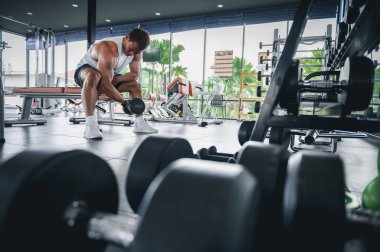 Spor salonunda ağırlık kaldıran kaslı vücut geliştirici Asyalı bir adam halterci halterli bir halterle egzersiz yapıyor. Fitness kas geliştirme konseptini çalıştırır.
