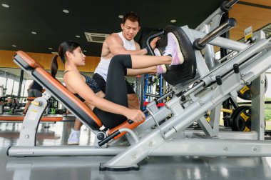 Spor salonunda genç bir bayana yardım eden kişisel antrenör ya da fitness eğitmeni.