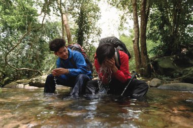 İki genç yürüyüşçü veya gezgin dağ nehrinde kayaların üzerinde oturur ve yüzünü dağ deresi suyuyla yıkamak için ellerindeki doğal suyun tadını çıkarırlar. Uzun bir yolculuktan sonra kendine gelir..