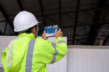 İnşaat Mühendisi, inşaat ve teftişi taramak için tabletler aracılığıyla teknoloji yazılımını kullanarak iş, bina bilgisi modeli veya BIM konseptinde artırılmış gerçekliği gösterir