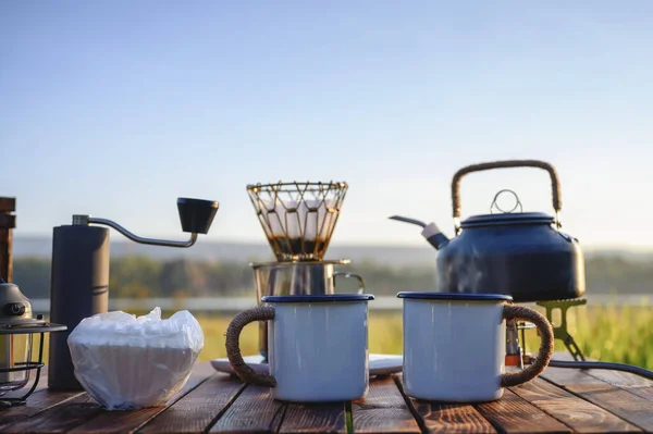 Outdoor coffee drink on wooden table with natural mountain background and soft sunrise, coffee drip with other equipment with copy space.