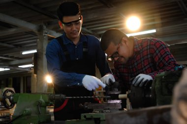 İşte teknisyenle Asyalı çırak genç mühendis tartışması ahşap delik açmak için makine bakımını inceliyor. Makine mühendisliği konseptinde ustalık..