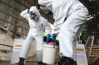 Kimyasal Güvenlik Uzmanları Kimyasal Risk Koruma Giysilerini Kimyasal Döküm Temizleme ve Bir Kova Taşıma, Endüstriyel Atık Temizleme ve Çevre Güvenliğinde Kurtarma İçin Giyindiler.
