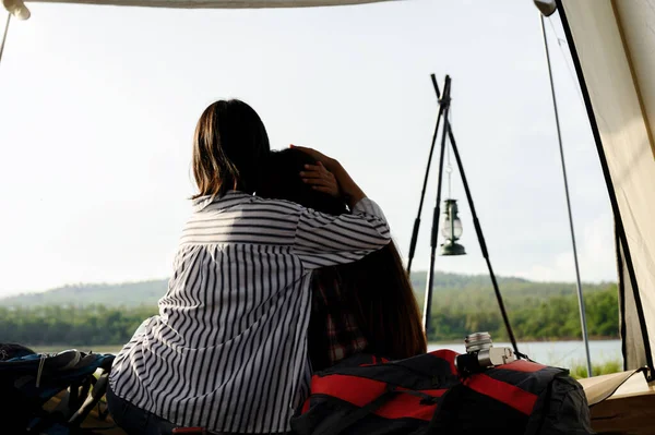 Close up Asian couple of young women sitting embrace and touching heads in their moment of intimacy and care in camping tent