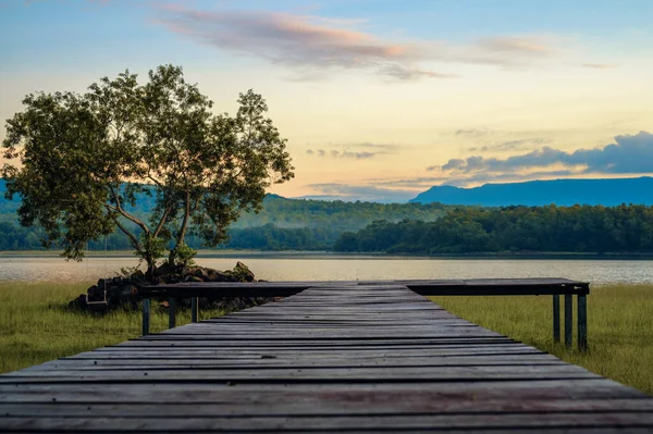 Wooden bridge terrace on the grass and nature lake with forest and mountain sky background. **Focus**