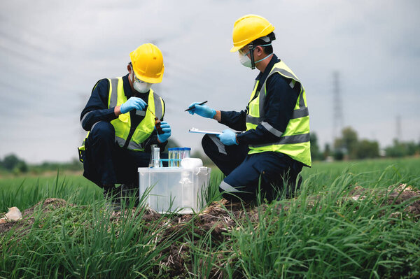 Два инженера-эколога проверяют качество воды и берут образцы воды на поле вблизи фермы, природные источники воды, возможно, загрязненные токсичными отходами или подозрительными местами загрязнения.