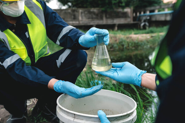 Инженеры-экологи берут пробы воды в бутылки в гнилых вонючих водоемах, которые могут быть загрязнены токсичными отходами или подозрительными местами загрязнения.