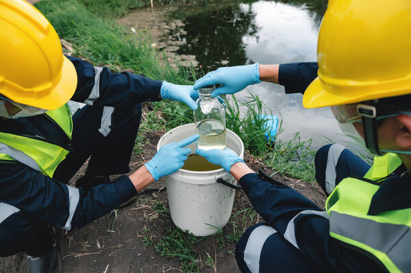 Инженеры-экологи берут пробы воды в бутылки в гнилых вонючих водоемах, которые могут быть загрязнены токсичными отходами или подозрительными местами загрязнения.