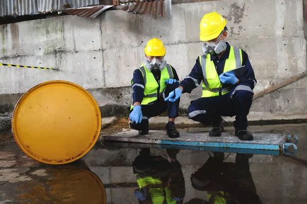 Çevre Mühendisliği 'nden iki memur gaz maskeli koruyucu ekipman giyip Depo Eski, Tehlikeli Yakıt Sızıntısı ve Çevre Konsepti' nde Petrol sızıntısı.