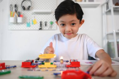 Asyalı Çocuk Elektronik İnşaatçıyla Eğleniyor ve Eğleniyor. Evdeki Devre Kuruluyla Öğrenme ve Deney. Geleceğin mucitleri için Beyin Geliştir, Uygula.