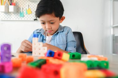 Asyalı Küçük Çocuk Evdeki Masada Renkli Plastik Küpler Oynuyor. Matematikte Sayma Küpü Öğrenme ve Eğitimi, Beyin ve Meditasyonu Oynarken Geliştirme.