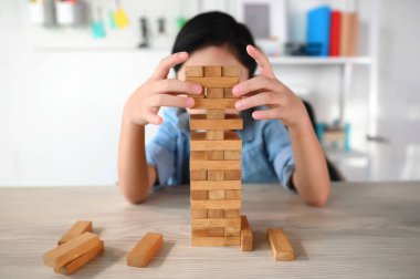 Çocuk Çocuk Evdeki Masada Jenga Oyunu Heyecan Veriyor. Dikkatli ve özenli Odaklan, Konsantre ol ve Yavaşça Gözlemle ve Denge Nesnelerini Korumak İçin Oynarken Çıkarmayı Yönet.