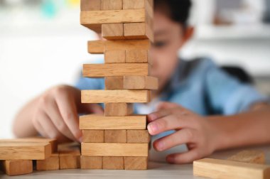Çocuk Çocuk Evdeki Masada Jenga Oyunu Heyecan Veriyor. Dikkatli ve özenli Odaklan, Konsantre ol ve Yavaşça Gözlemle ve Denge Nesnelerini Korumak İçin Oynarken Çıkarmayı Yönet.