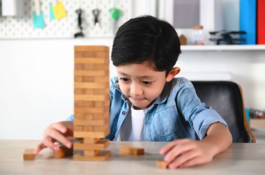 Çocuk Çocuk Evdeki Masada Jenga Oyunu Heyecan Veriyor. Eğlence ve Yetenek serbest bırakılıyor. Dikkatli ve özenli ol, konsantre ol ve oynarken yavaşça çıkar. Nesneleri çalıştır ve dengelemeyi öğren.