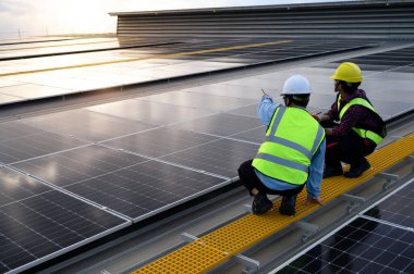 Uzman teknisyenler, mühendisler ve ustabaşı güneş fotovoltaik panellerinin kalitesini çatıdaki teknoloji tabletleriyle kontrol etmek için çalışıyor..