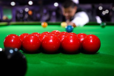 Snooker kırmızı top grubu bilardo masasına kırmızı top atarken arka planda bilardo oyuncusu bulanıklığı ile ayarlandı.