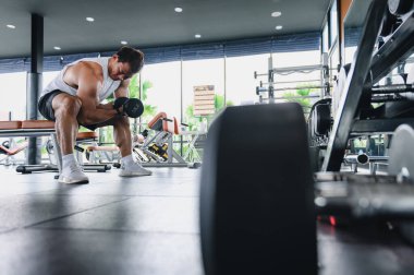 Spor salonunda ağırlık kaldıran kaslı vücut geliştirici Asyalı bir adam halterci halterli bir halterle egzersiz yapıyor. Fitness kas geliştirme konseptini çalıştırır.
