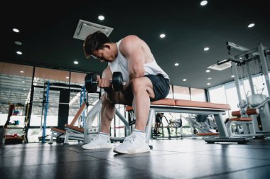 Spor salonunda ağırlık kaldıran kaslı vücut geliştirici Asyalı bir adam halterci halterli bir halterle egzersiz yapıyor. Fitness kas geliştirme konseptini çalıştırır.