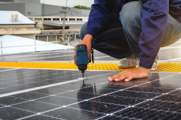 工場屋根の建物の昼間のサポートポイントで太陽電池パネルか太陽光発電を取付ける用具を使用する技術者 — ストック写真