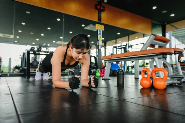 Asyalı fit bir kadın spor salonunda kalas çekirdek egzersizi yapıyor, yeni başlayanlar için Crossfit egzersiz yapıyor ve kardiyo çalışması yapıyor..