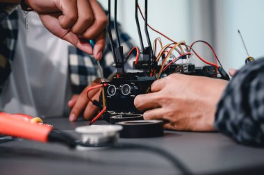 Robot malzemeleri monte eden Asyalı Mühendis Öğrenciler. Mekanik Kontrol 'ü öğrenirken, robotlar bilgisayar, elektrik, mekanik ve algılamayı birleştirir. Mühendisleri ve Geliştirme Konseptini Güçlendirme.