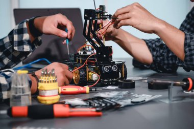 Robot malzemeleri monte eden Asyalı Mühendis Öğrenciler. Mekanik Kontrol 'ü öğrenirken, robotlar bilgisayar, elektrik, mekanik ve algılamayı birleştirir. Mühendisleri ve Geliştirme Konseptini Güçlendirme.