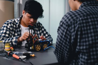 Robot malzemeleri monte eden Asyalı Mühendis Öğrenciler. Mekanik Kontrol 'ü öğrenirken, robotlar bilgisayar, elektrik, mekanik ve algılamayı birleştirir. Mühendisleri ve Geliştirme Konseptini Güçlendirme.