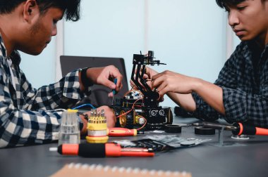 Robot malzemeleri monte eden Asyalı Mühendis Öğrenciler. Mekanik Kontrol 'ü öğrenirken, robotlar bilgisayar, elektrik, mekanik ve algılamayı birleştirir. Mühendisleri ve Geliştirme Konseptini Güçlendirme.