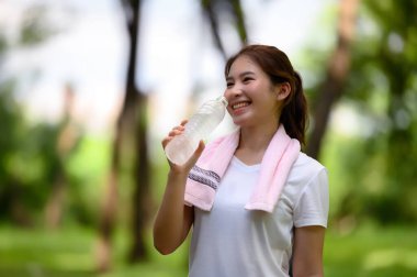 Yeşil Park 'ta koşu ve egzersiz yaptıktan sonra susuzluğu gideren Asyalı Kadın Tazeleyici Su İçeceği