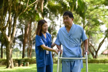 Asyalı Kadın Doktor Kıdemli Hastaya Yardım Ediyor ve Tedavi sırasında Teşvik Ediyor. Yürüyen Aids 'li Asyalı Emekli Hastaların Rehabilitasyon veya Fiziksel Terapisi.