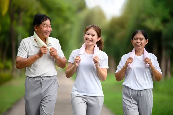 Asian Seniors and Daughter Jogging and Relaxing in the Park, Family Bonding in Nature, Seniors and Family Enjoying Exercise and Relaxation in the Green Park, Health Care and Family Bonding Concept