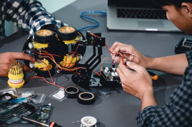 Robot malzemeleri monte eden Asyalı Mühendis Öğrenciler. Mekanik Kontrol 'ü öğrenirken, robotlar bilgisayar, elektrik, mekanik ve algılamayı birleştirir. Mühendisleri ve Geliştirme Konseptini Güçlendirme.