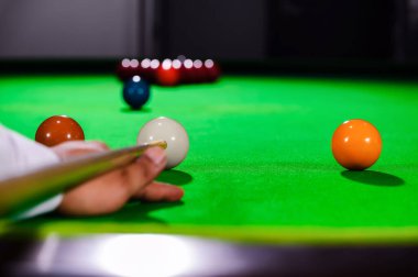 Profesyonel bilardo oyuncusunun eli bilardo masasına beyaz top atmayı hedefliyor..