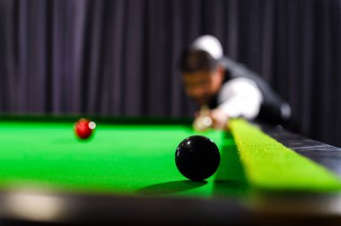 Snooker siyah bir top ve rakip bulanık bilardo oyuncusu arka plandaki bilardo masasına siyah top koyarken.