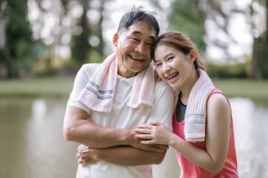 Spor giyim sektöründe Asya 'lı yaşlı baba ve kızı yeşil bir parkta birbirlerine sevgi ve ilgi gösteriyorlar. Sağlık ve aile bağları.