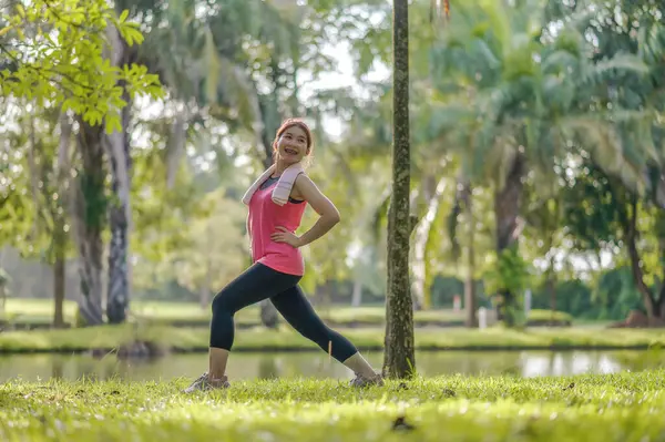 Asian young women enjoy exercising in the public park. Stretching the body and taking a breath of fresh air. The fresh air helps to feel more energized.