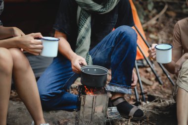 Yağmur ormanlarında ve Kamp alanında rahatça oturup kahve ve su içerken, Genç İnsanlar Trekking Grubu 'nun bir kamp sobasıyla Kaynayan Su' nun yakın çekimi.