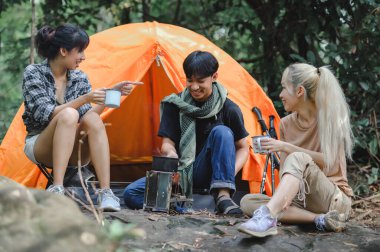 Gençler, Yağmur Ormanları 'nda Oturan Gevşek Konuşmalar ve Kamp Sobası ile Su Kaynatan Genç Seyahat Grubu. Kamp alanı. Seyahatlerde kahve ve su içmek..