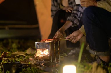 Sırt çantalı grubun vahşi ortamında ızgara ızgarasına yakın çekim. Yürüyüş grupları için ızgara yemekler, doğada kamp yapmak, sıcak ve davetkar bir atmosferle gece yemek pişirmek..