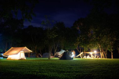 Geceleri çimen avlusunda Glamping çadırı ve karanlık mavi gökyüzü alacakaranlık vakti altında sıcak gece ışığı, tatilde aile tatil kampı grubu dinlenme, aile turistlerinin kamp yapma manzarası..