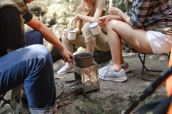 Close-up of Boiling Water with a Camp Stove of a Young People Trekking Group while Sitting Relaxed in the Rainforest and Campsite Drinking Coffee and Water.