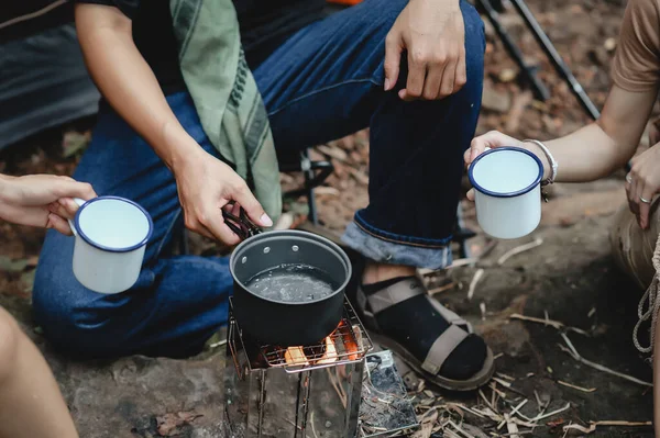 Close-up of Boiling Water with a Camp Stove of a Young People Trekking Group while Sitting Relaxed in the Rainforest and Campsite Drinking Coffee and Water.