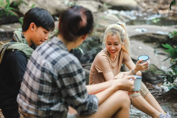 Young People Trekking Group Holding the Camping Water Cup is Clean Water for Drink. Hikers\' Refreshment Break, Campsite Drinking Coffee and Water on Trekking Trips.