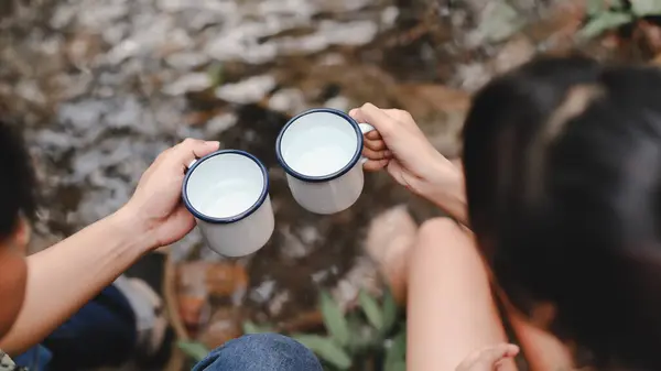 Close-up Top View of Holding Water Cups for Drinking. Clean Water Drink in the White Cups in the Forest on Natural Stream Background. Water Cleanliness and Hygiene on Trekking Trips