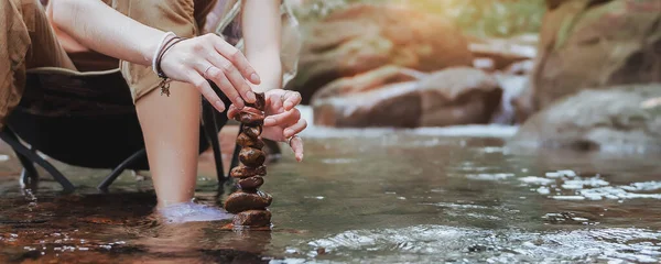 Close-up Hand of woman to build natural stone arrangements, Balance stones in the stream, Trying management to find a balance. Concept of management and harmony. Banner size with Copy Space.