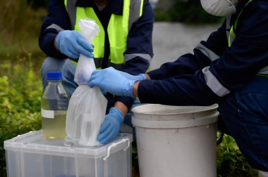 Çevre Mühendisleri Doğal Su Kaynakları 'ndaki kötü kokan su örneklerini şişeye koyup plastik poşetlere koydular. Zehirli Kirlilik Alanlarının Kirlettiği Suyu..