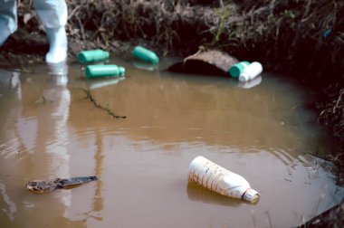 Doğal su kaynağında kimyasal dolu çöp şişeleri var. Su kirliliği kavramı.