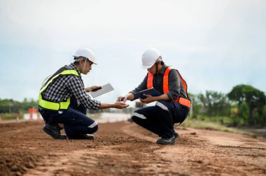 Otoyol mühendisleri inşaat inşaatı için yan toprağa dokunup teftiş ediyor. İnşaat mühendisliği, karayolu inşaatında müfettiş olarak çalışıyor..